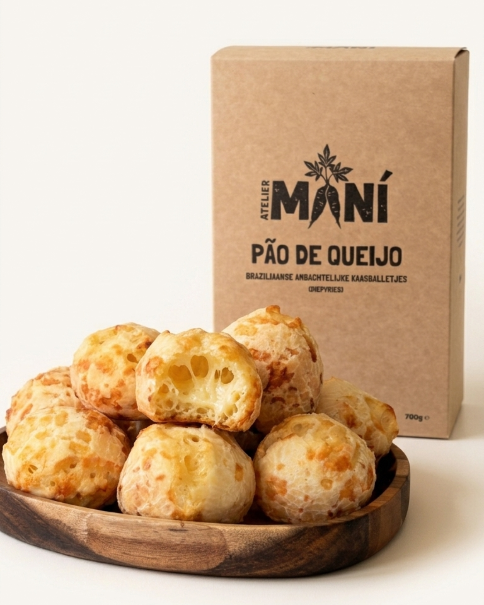 Baked pães de queijo in a wooden bowl with an Atelier Maní box on a cream  color background.